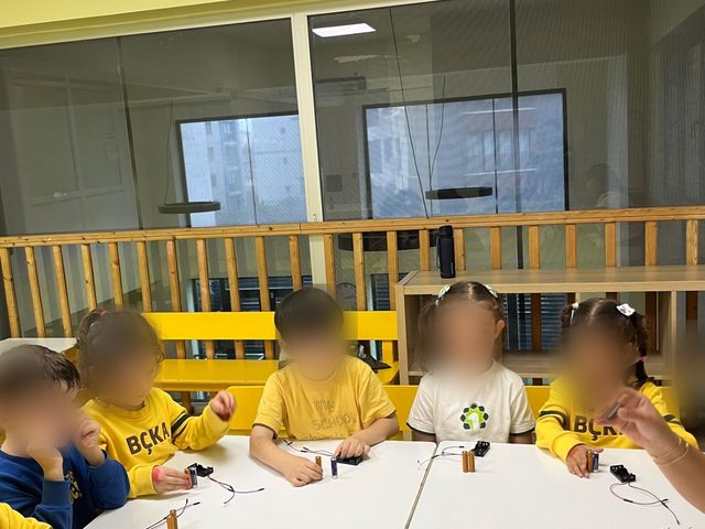 Robotik kodlama dersinde pil ve kablolarla devre kuran çocuklar