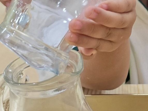 Cam sürahiden su döken bir çocuğun elleri