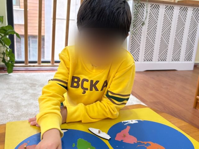 Yapboz dünya haritasıyla çalışan bir çocuk
